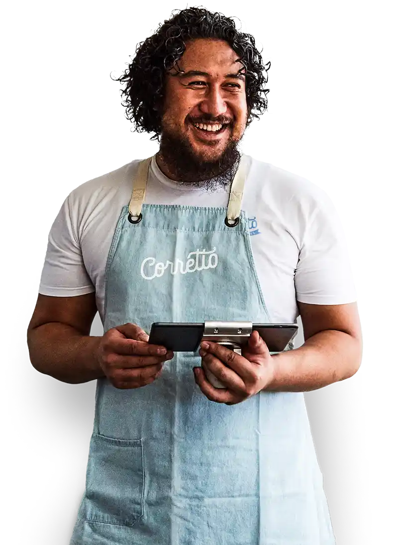 Un propriétaire de restaurant souriant portant un t-shirt et un tablier alors qu'il utilise une tablette avec le logiciel de caisse Lightspeed Restaurant.